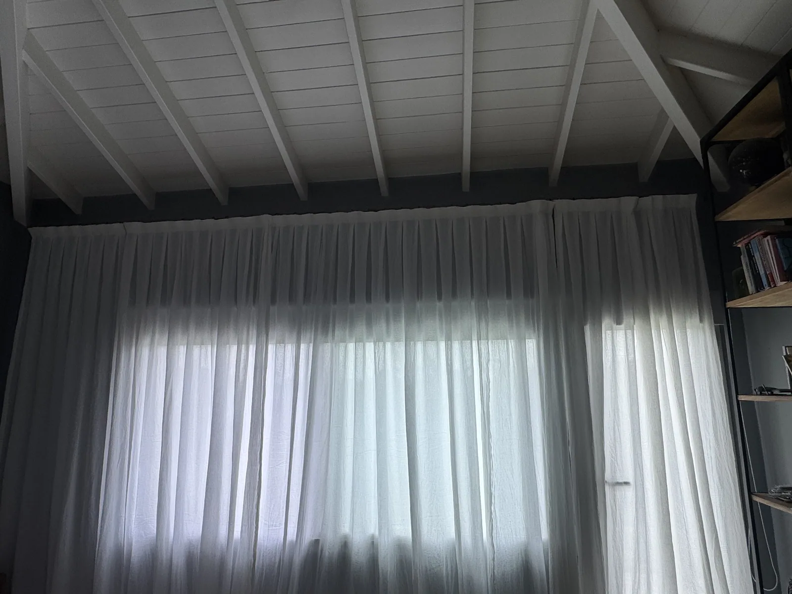 Sala con techo cabriada y cortinas sheer cerradas